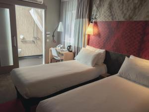 um quarto de hotel com duas camas e uma escrivaninha em ibis Glasgow City Centre – Sauchiehall St em Glasgow