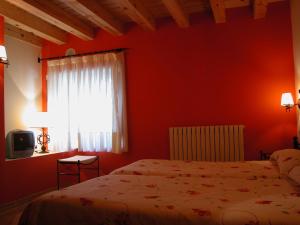 Dormitorio rojo con cama y ventana en C.T.R. Camino de la Fuentona, en Cabrejas del Pinar