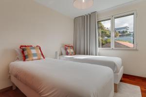 due letti in una stanza bianca con una finestra di Funchal City Nest a Funchal