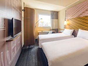 a hotel room with two beds and a flat screen tv at Hotel ibis Lisboa Liberdade in Lisbon