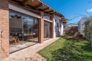a brick house with large glass windows and a patio at Cocciu D'amuri Luxury in Portopalo