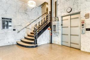 a staircase in a building with a clock on the wall at Modern Elegance: Timeless Crawfordsville Studio! in Crawfordsville
