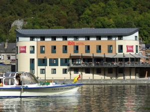 un barco en el agua frente a un edificio en ibis Dinant Centre, en Dinant