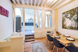 Un comedor con mesa y sillas y una gran ventana. en 6 Guests Flat in heart of Paris - Pompidou, en París