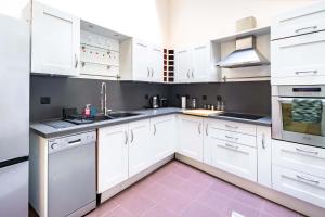 Una cocina blanca con gabinetes y electrodomésticos blancos. en 6 Guests Flat in heart of Paris - Pompidou, en París