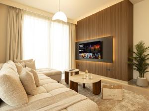 a living room with a white couch and a tv at Forte Suites by Prestige Nest in Dubai
