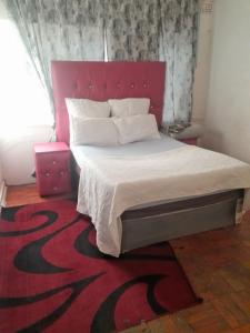 ウェルコムにあるJT Guesthouseの赤いヘッドボードが付いた大きなベッドのある寝室