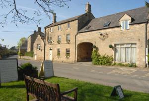 un bâtiment avec un banc devant lui dans l'établissement Bay Tree Cottage, à Shipton under Wychwood