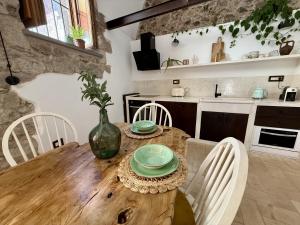 una cucina con un tavolo di legno e sedie bianche di Molinu a Santu Lussurgiu