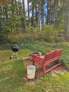 a red bench and a grill in a yard at Romantic countryside SAUNA Cottage in Maakeski
