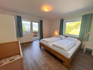 a bedroom with a bed and two large windows at Apartment Benjamin by Interhome in Hollersbach im Pinzgau