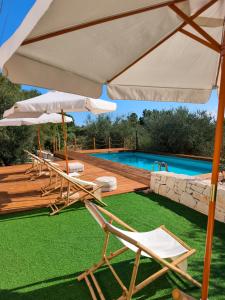 un groupe de chaises et de parasols à côté d'une piscine dans l'établissement LocoMura, à Locorotondo