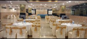 un salón de banquetes con mesas blancas y arcos de oro en The Royal Retreat, en Ranchi 16 fotos más