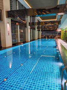 a large swimming pool with blue tiles on the floor at Condo Living - Pool, Balcony, Gym, Fast WiFi in Manila