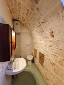 une salle de bain avec un lavabo et un mur en pierre dans l'établissement LocoMura, à Locorotondo
