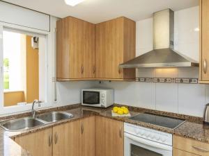 a kitchen with wooden cabinets and a sink and a microwave at Apartment República Dominicana by Interhome in Miami Platja