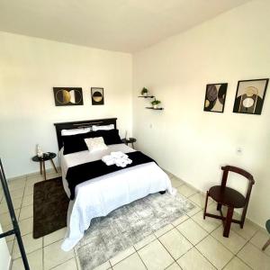 una camera con un letto bianco e nero e una sedia di Pnz Loft a Petrolina