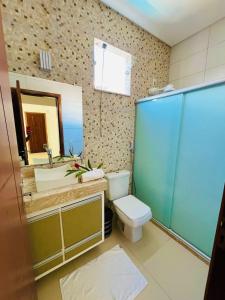 a bathroom with a toilet and a sink and a mirror at Casa Lalivi Trancoso in Porto Seguro