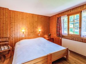 a bedroom with wooden walls and a bed and a window at Apartment Vermont 8 by Interhome in Villars-sur-Ollon