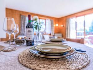 a table with plates and glasses and a bottle of wine at Apartment Vermont 8 by Interhome in Villars-sur-Ollon