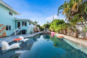 una piscina con sillas blancas y una casa en Luxury Villa Pool Jacuzzi Cinema and Game Room, en Fort Lauderdale