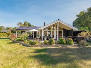 une maison avec une terrasse couverte fleurie dans la cour dans l'établissement Holiday Home Arisa - 300m from the sea by Interhome, à Gedesby