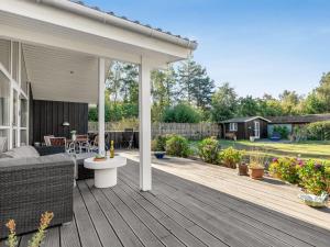 une terrasse en bois avec un canapé et une table dans l'établissement Holiday Home Arisa - 300m from the sea by Interhome, à Gedesby