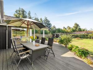 une table et des chaises avec un parasol sur une terrasse dans l'établissement Holiday Home Arisa - 300m from the sea by Interhome, à Gedesby