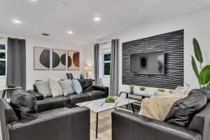 a living room with black leather furniture and a tv at Casa Stella Tropical Pool Beach 8 min in Hollywood