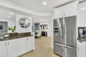 a kitchen with white cabinets and a stainless steel refrigerator at Casa Stella Tropical Pool Beach 8 min in Hollywood