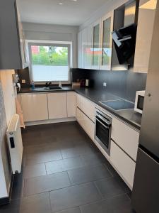 a large kitchen with white cabinets and a window at Haus Auszeit in Cremlingen +6 photos