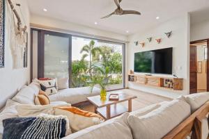 a living room with white furniture and a large window at Tranquil Jungle Retreat w Pool Bikes and Walk to Town in San Francisco