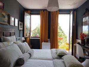 a bedroom with two beds and a large window at Brockwood Manor Tea House - Valdilana in Valle Mosso