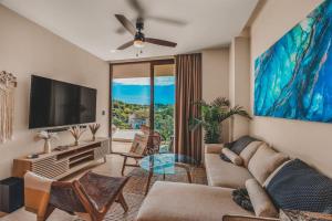 a living room with a couch and a flat screen tv at Luxe 2BR 2BA w 3 Pools Plunge Rooftop Family in Sayulita