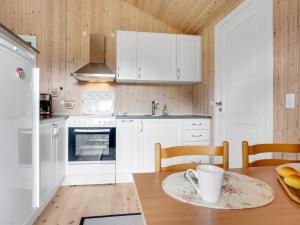 a kitchen with white cabinets and a table with a cup at Holiday Home Aleth - 800m from the sea by Interhome in Gedesby