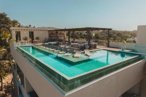 a swimming pool with lounge chairs on top of a building at Elite 2BR 2BA Ocean Views Rooftop Pool in Sayulita