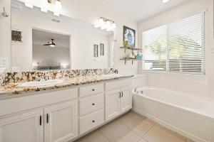a white bathroom with a tub and a sink and a mirror at The Fiddyment Roost in Roseville +56 photos