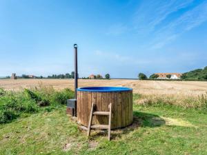 a wooden barrel with a chair in a field at Holiday Home Makrina - 300m from the sea by Interhome in Harpelunde
