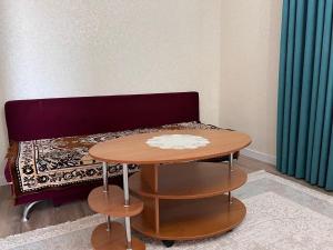 a table in front of a couch with a bed at Aral Guest House in Aralʼsk