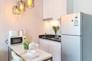 チェンマイにあるSpecious Condo At Nimman With Rooftop Poolの白い冷蔵庫とテーブルのある小さなキッチン