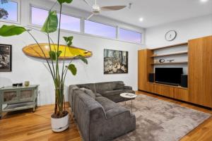 Una sala de estar con un sofá y una tabla de surf amarilla en la pared. en Barnett Bush Retreat, en Torquay