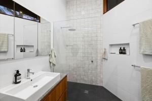 Un baño blanco con lavabo y ducha. en Barnett Bush Retreat, en Torquay 12 fotos más