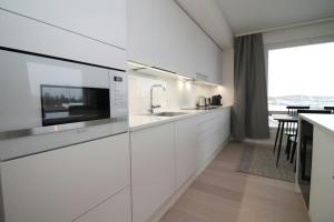a white kitchen with a sink and a counter at Spacious Apartment for 2 with Sauna in V in Iso-Heikkilä