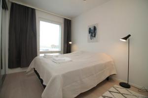a white bedroom with a bed with white sheets and a window at Spacious Apartment for 2 with Sauna in V in Iso-Heikkilä