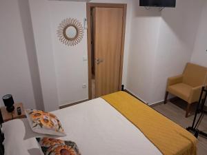 a bedroom with a bed and a chair and a mirror at AL Rossadas Carqueija in Arganil