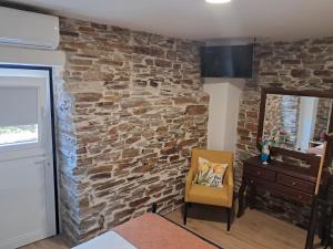 a room with a stone wall and a yellow chair at AL Rossadas Carqueija in Arganil +5 photos