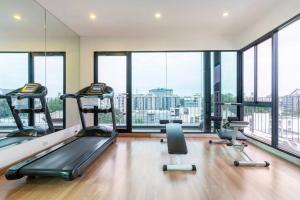 un gimnasio con máquinas cardiovasculares y ventanas grandes en Stay Nimman Center with Rooftop Pool, en Chiang Mai