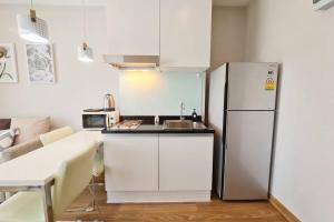 een witte keuken met een koelkast en een tafel bij Lovely 1BR with Rooftop Pool in Nimmanhemin 605 in Chiang Mai