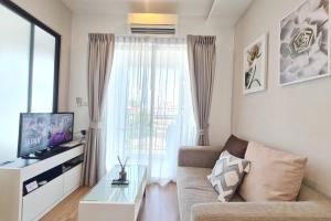 een woonkamer met een bank en een raam bij Lovely 1BR with Rooftop Pool in Nimmanhemin 605 in Chiang Mai