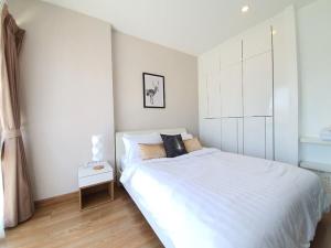 een witte slaapkamer met een bed en een nachtkastje bij Live in Nimman High Floor And Rooftop Pool in Chiang Mai